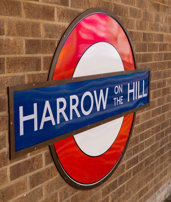 The image depicts a train platform at Mill Hill Broadway station, with railway tracks running parallel along the left side. The platform surface is made of concrete, featuring a tactile yellow warning